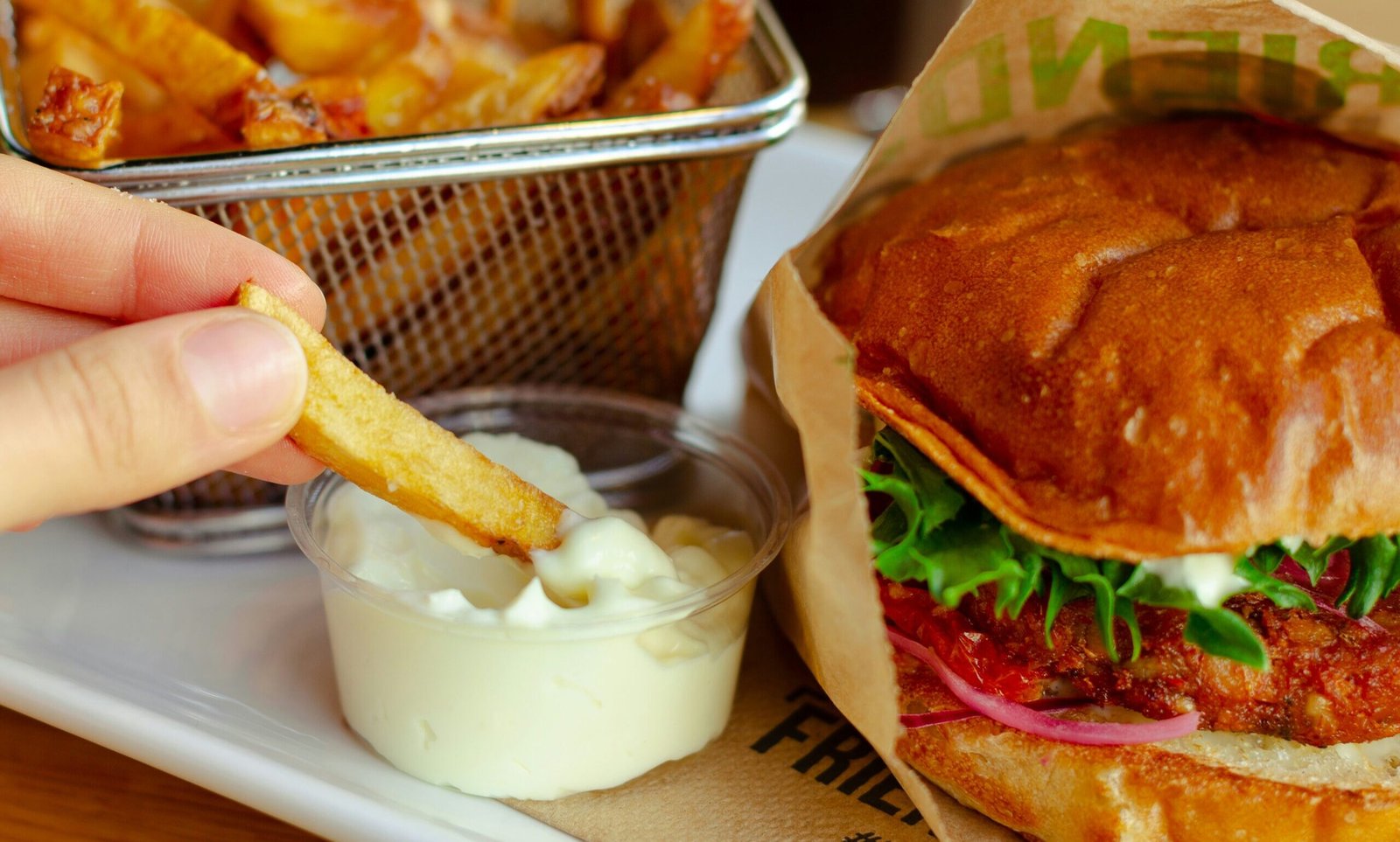 zdjęcie majonezu w plastikowym pojemniczku obok frytek i hamburgera