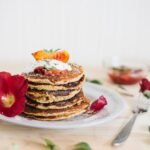zdjęcie bezglutenowych pancakes ułożonych w stosik na talerzu udekorowanym kwiatami i liśćmi