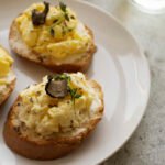 zdjęcie bezglutenowej pasty jajecznej na bezglutenowych kromkach chleba udekorowanej plastrem trufli i podanej na białym talerzu