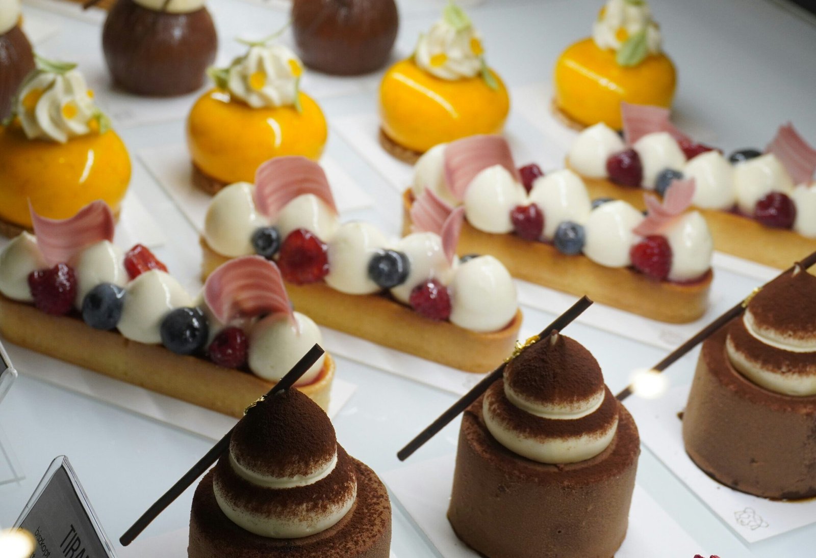 Wykwintne bezglutenowe desery z owocami i kremem w witrynie cukierni.