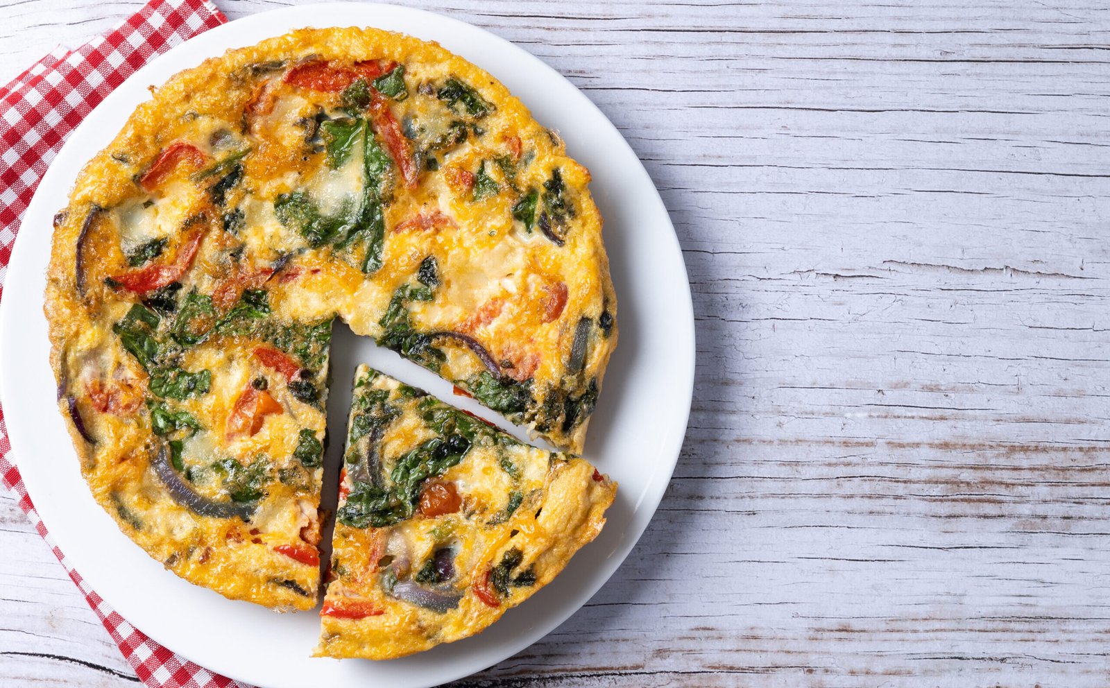 Frittata bezglutenowa z warzywami, podana na białym talerzu, widok z góry.