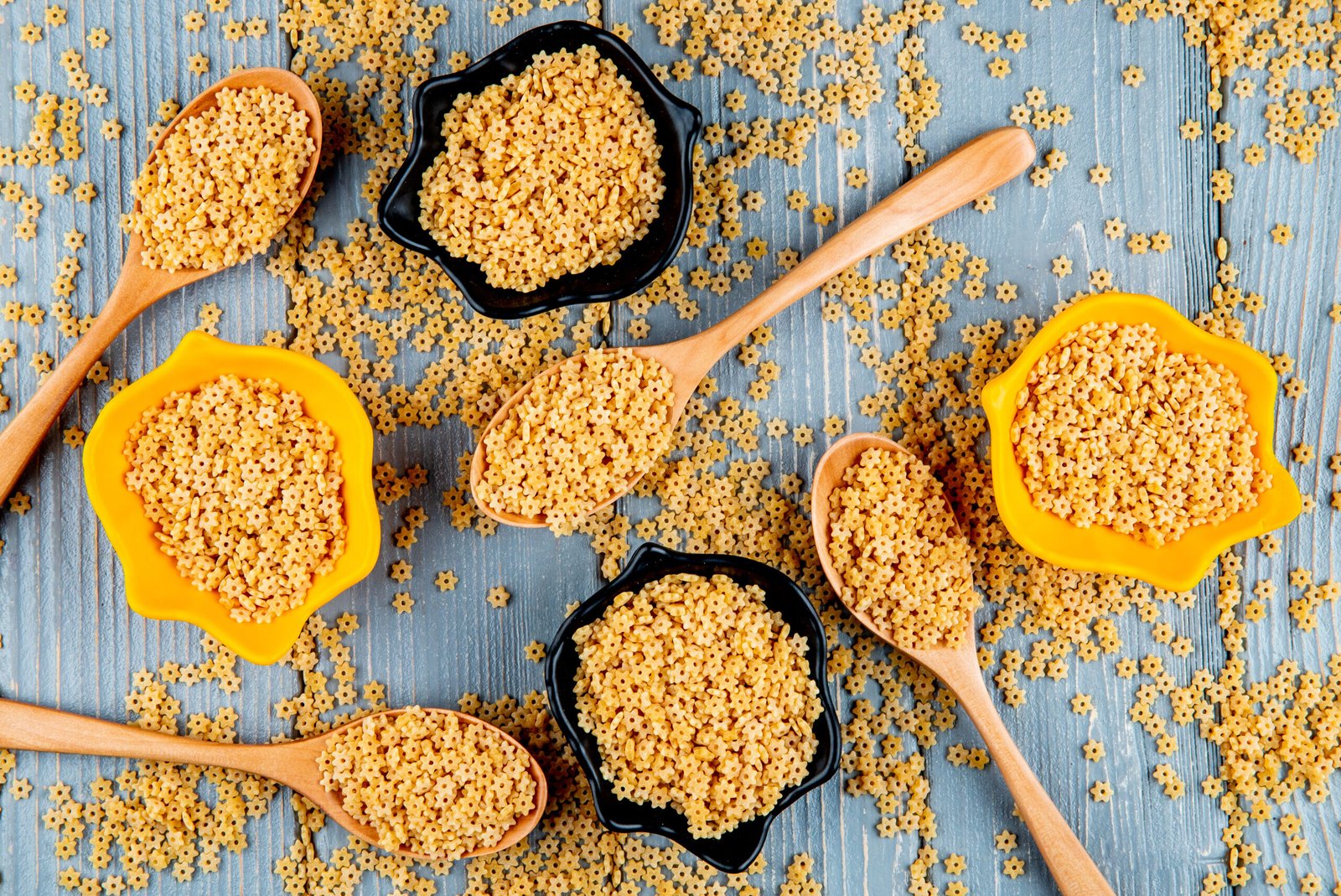 Kasza bezglutenowa w drewnianych łyżkach i miseczkach na drewnianym stole – naturalny produkt w kuchni bezglutenowej, pełen smaku i wartości odżywczych.