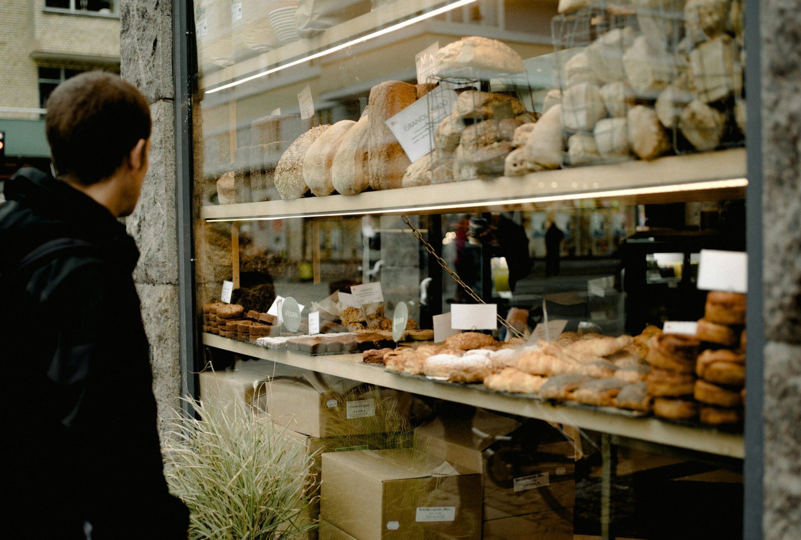 zdjęcie witryny piekarni z zewnątrz i człowiek przyglądający się wypiekom