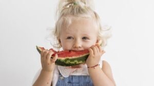 Małe dziecko je kawałek arbuza – zdrowa dieta bezglutenowa u dzieci z celiakią.