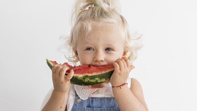 Małe dziecko je kawałek arbuza – zdrowa dieta bezglutenowa u dzieci z celiakią.