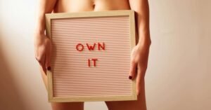 zdjęcie części ciała kobiety trzymającej tablicę z napisem "own it" symbolizującej zdrowie jelit