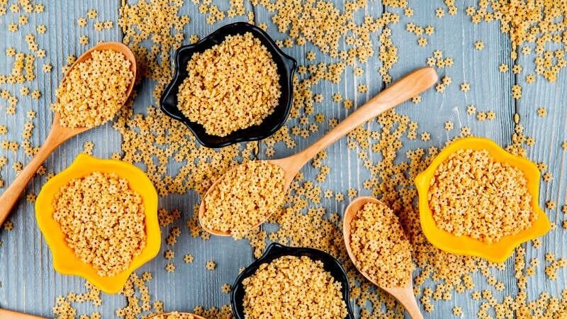 Kasza bezglutenowa w drewnianych łyżkach i miseczkach na drewnianym stole – naturalny produkt w kuchni bezglutenowej, pełen smaku i wartości odżywczych.