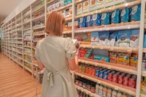 zdjęcie kobiety stojącej tyłem i czytającej etykiety w bezglutenowym dziale w supermarkecie