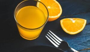 Sok pomarańczowy i świeże plastry pomarańczy – naturalne źródło witaminy C w diecie bezglutenowej.