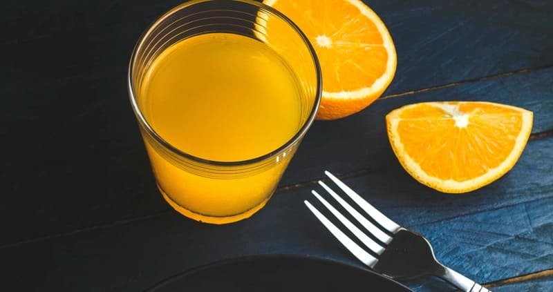 Sok pomarańczowy i świeże plastry pomarańczy – naturalne źródło witaminy C w diecie bezglutenowej.