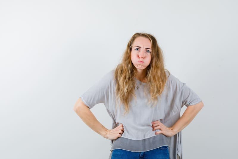 zdjęcie kobiety z nadętymi policzkami i trzymającej się za brzuch co symbolizuje złe samopoczucie z powodu glutenu