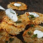 zdjęcie placków z cukinii bez mąki w towarzystwie szczypiorku oraz kwaśnej śmietany