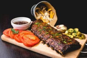 zdjęcie przedstawia danie bez glutenu: żeberka z dodatkami na drewnianej desce