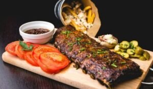 zdjęcie przedstawia danie bez glutenu: żeberka z dodatkami na drewnianej desce