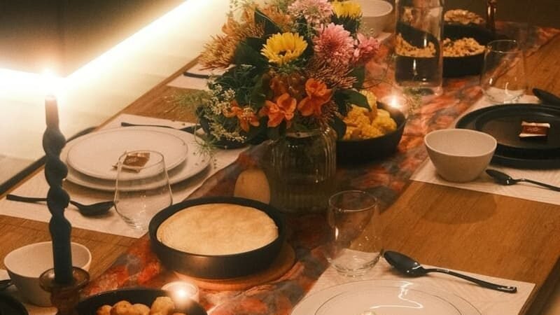 Sylwestrowy stół z dekoracjami i świecami, talerze z przekąskami, miski z daniami do dzielenia oraz nakrycia przygotowane na bezglutenową imprezę w kameralnym klimacie.