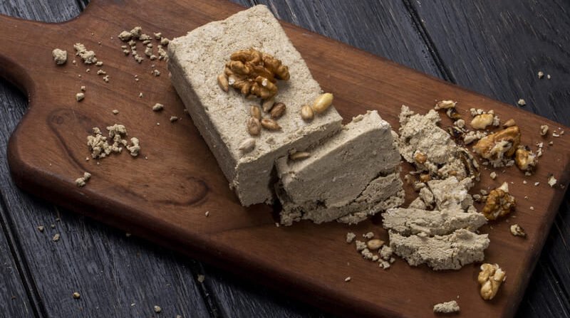 Chałwa sezamowa z orzechami włoskimi pokrojona na kawałki na drewnianej desce