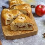 Bezglutenowe ciasto ucierane z jabłkami, pokrojone na kawałki i podane na drewnianej desce, z widocznymi kawałkami jabłek w środku.