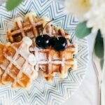 zdjęcie bezglutenowych gofrów na kolorowym talerzu, podane z wiśniami i cukrem pudrem