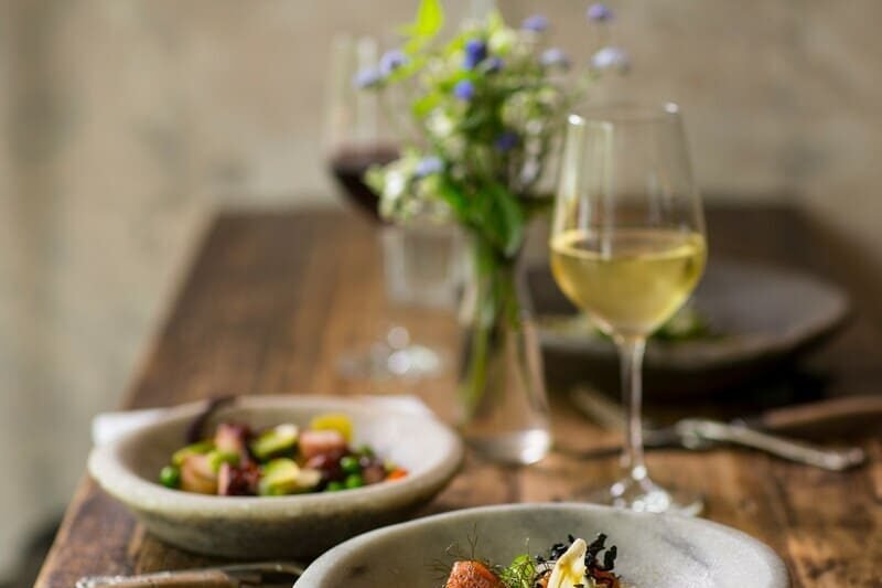 Eleganckie danie bezglutenowe z rybą i warzywami podane w restauracji, kieliszek białego wina