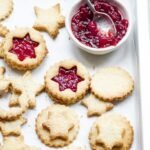 zdjęcie przedstawiające kruche ciasteczka bezglutenowe ułożone na sobie, część jest przełożona konfiturą, a część nie ma dodatków