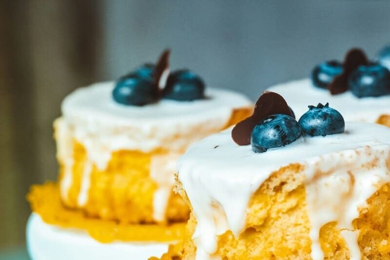 Bezglutenowe serniczki z polewą waniliową i borówkami, dekoracja z czekolady