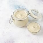 zdjęcie domowego majonezu bez glutenu w przezroczystym słoiczku z zamykaniem oraz w miseczce, na kolorowym tle