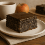 Makowiec japoński bezglutenowy z polewą czekoladową, podany na talerzyku przy filiżance herbaty na drewnianym stole, w naturalnej domowej aranżacji.