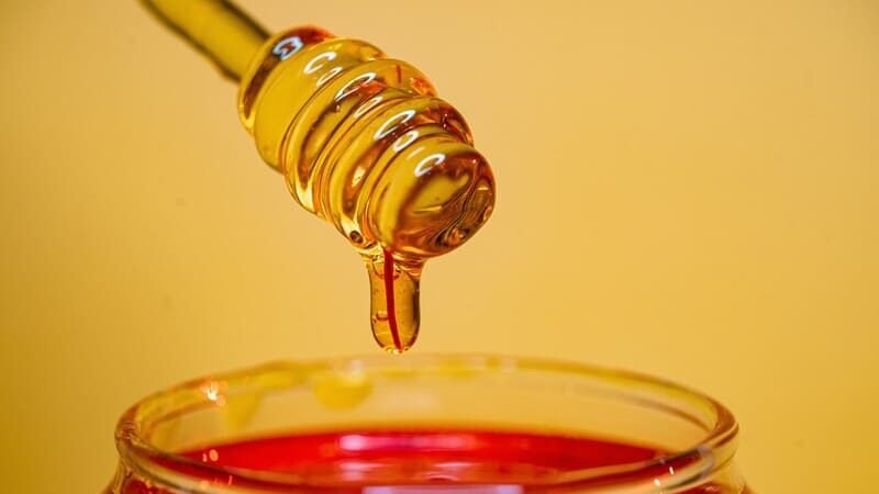 zdjęcie łyżki do miodu zanużonej w miodzie w słoiku