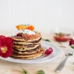 zdjęcie bezglutenowych pancakes ułożonych w stosik na talerzu udekorowanym kwiatami i liśćmi