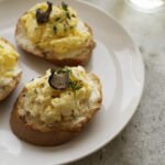 zdjęcie bezglutenowej pasty jajecznej na bezglutenowych kromkach chleba udekorowanej plastrem trufli i podanej na białym talerzu