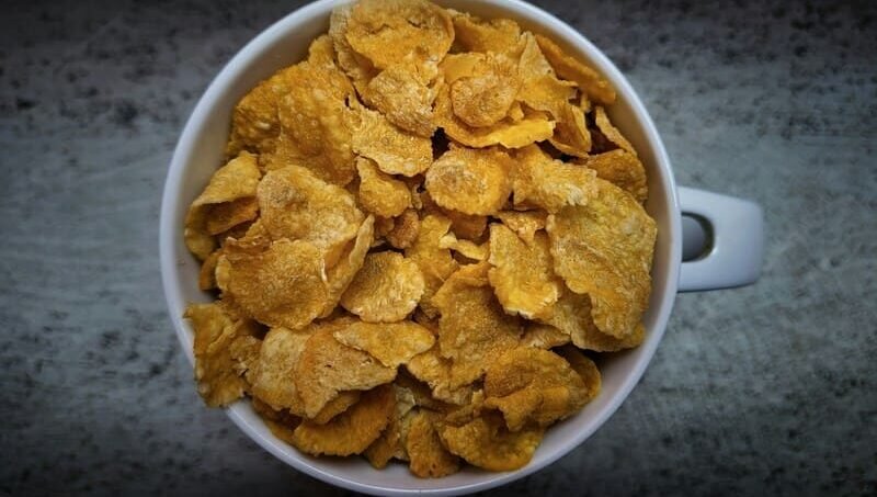 zdjęcie płatków kukurydzianych w dużym kubku z uchem na ciemnym tle