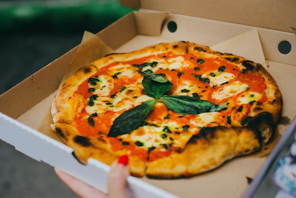 Bezglutenowa pizza margherita z mozzarellą, sosem pomidorowym i świeżą bazylią w pudełku na wynos