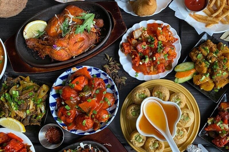 Tradycyjne dania kuchni indyjskiej, przystawki, chlebki i potrawy serwowane na kolorowym stole, bezglutenowe opcje