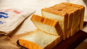 Kromki białego chleba pszennego ułożone na desce – przykład produktu zbożowego o wysokiej zawartości glutenu.