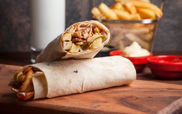 Bezglutenowy kebab w lawaszu z mięsem, warzywami i sosem, podawany na drewnianej desce – gluten free kebab w Warszawie dla osób na diecie bezglutenowej.