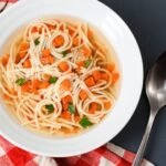 Makaron bezglutenowy do rosołu w klarownym bulionie z warzywami, podany w białej misce – domowy makaron bez glutenu