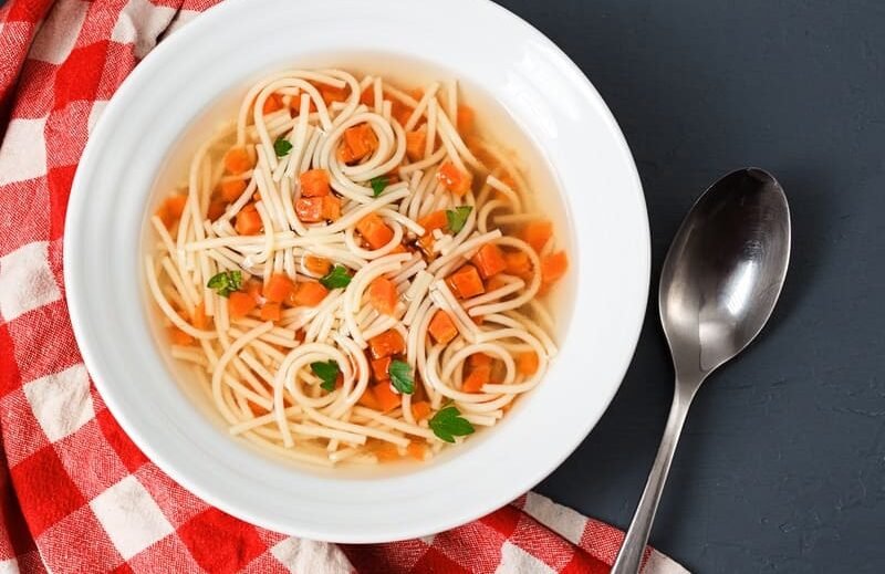 Makaron bezglutenowy do rosołu w klarownym bulionie z warzywami, podany w białej misce – domowy makaron bez glutenu