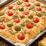 Bezglutenowa focaccia z oliwą, oliwkami, rozmarynem i pomidorkami koktajlowymi, świeżo upieczona na blaszce w domowym, naturalnym otoczeniu