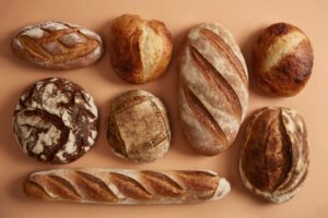 Różne rodzaje chleba bez glutenu – świeżo upieczone bochenki na jasnym tle.