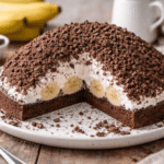 Bezglutenowy kopiec kreta na talerzu – czekoladowe ciasto z bananami, kremem śmietankowym i pokruszonym biszkoptem w domowym otoczeniu