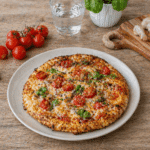 Pizza z serka wiejskiego bez mąki, złocisty i lekko przypieczony spód, z dodatkiem mozzarelli, pomidorków i ziół, podana w domowym otoczeniu, zdjęcie z oddalenia