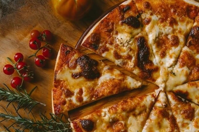Bezglutenowa pizza z serem mozzarella i pomidorami podana na drewnianym stole