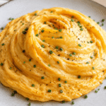 Puszysty omlet huragan o wirującej strukturze i kremowym środku podany na talerzu z posypką ze szczypiorku.