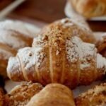 Kruche rogaliki bezglutenowe z nadzieniem, przygotowane z ciasta francuskiego bez glutenu i oprószone cukrem pudrem
