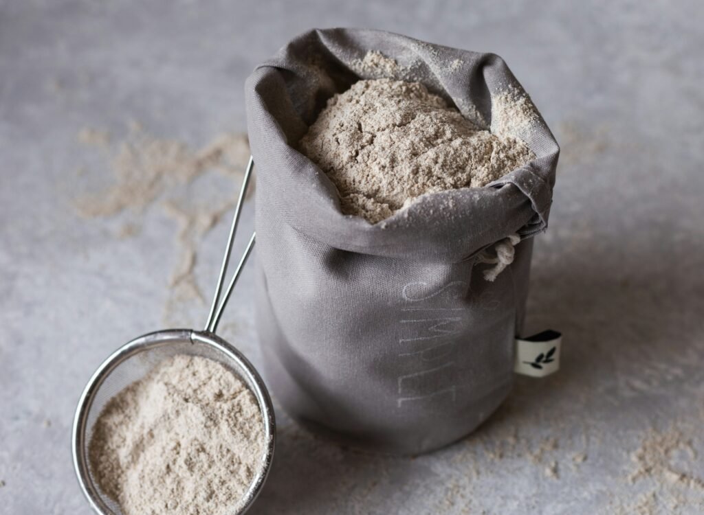 mąka gryczana (1) zdjęcie przedstawiające materiałowy woreczek z mąką gryczaną i sitko wypełnione mąką gryczaną