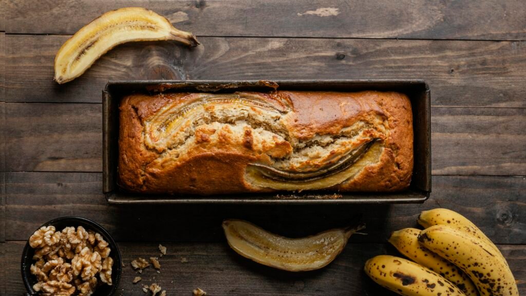 bezglutenowy chlebek bananowy bezglutenowy chlebek bananowy w keksówce na stole w towarzystwie bananów i orzechów włoskich