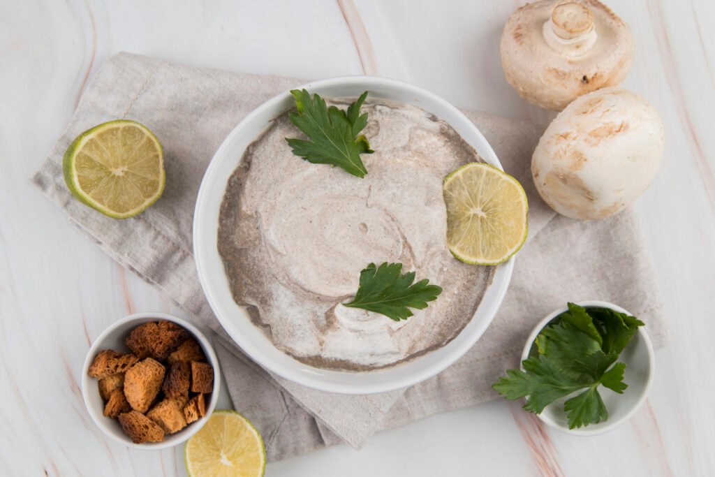 smalec z fasoli zdjęcie smalcu bez glutenu podanego w białej miseczce, z dodatkiem liści pietruszki i plasterka limonki