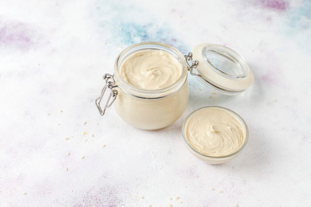 majonez bezglutenowy zdjęcie domowego majonezu bez glutenu w przezroczystym słoiczku z zamykaniem oraz w miseczce, na kolorowym tle