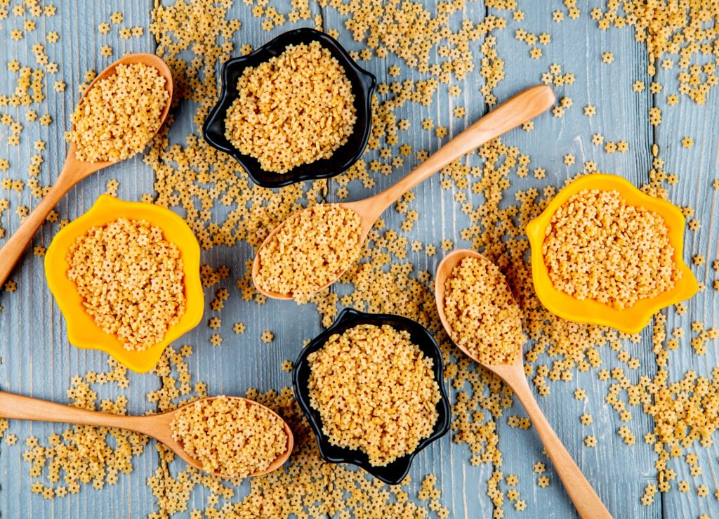 Kasza bezglutenowa w drewnianych łyżkach i miseczkach na drewnianym stole – naturalny produkt w kuchni bezglutenowej, pełen smaku i wartości odżywczych.