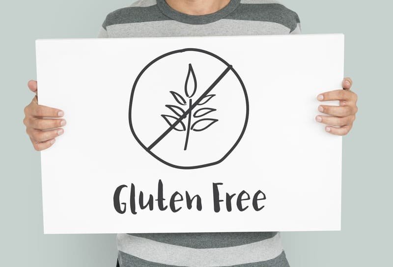 celiakia co to Osoba trzyma tablicę z symbolem przekreślonego kłosa i napisem Gluten Free – oznaczenie diety bezglutenowej